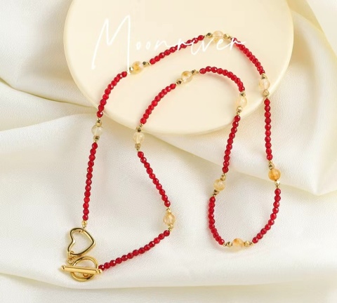 Delikatny naszyjnik z czerwonych koralików ze złotymi detalami.